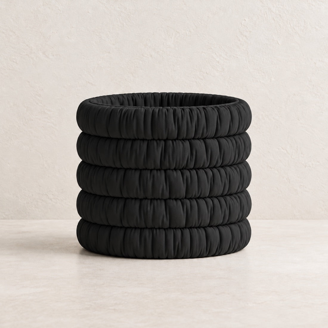Mossmallow Planter in Black (#000000), empty pot with warm plaster background and pale tabletop